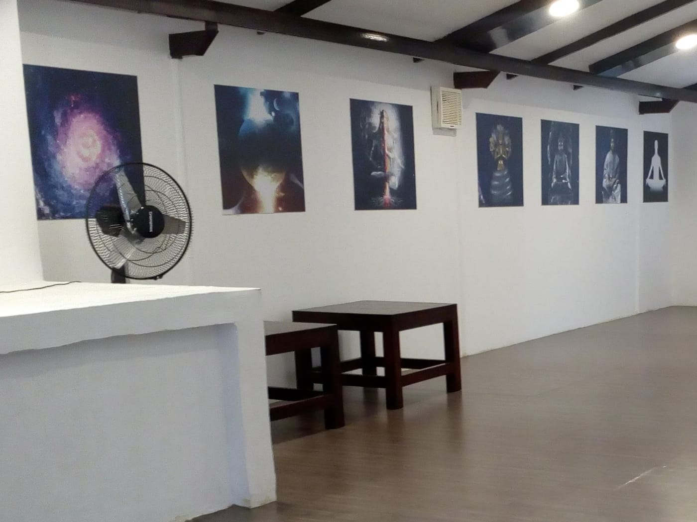 The far end of the hall at VHG Thiruvananthapuram, hung with prints and a Shanthi Mantra plaque
