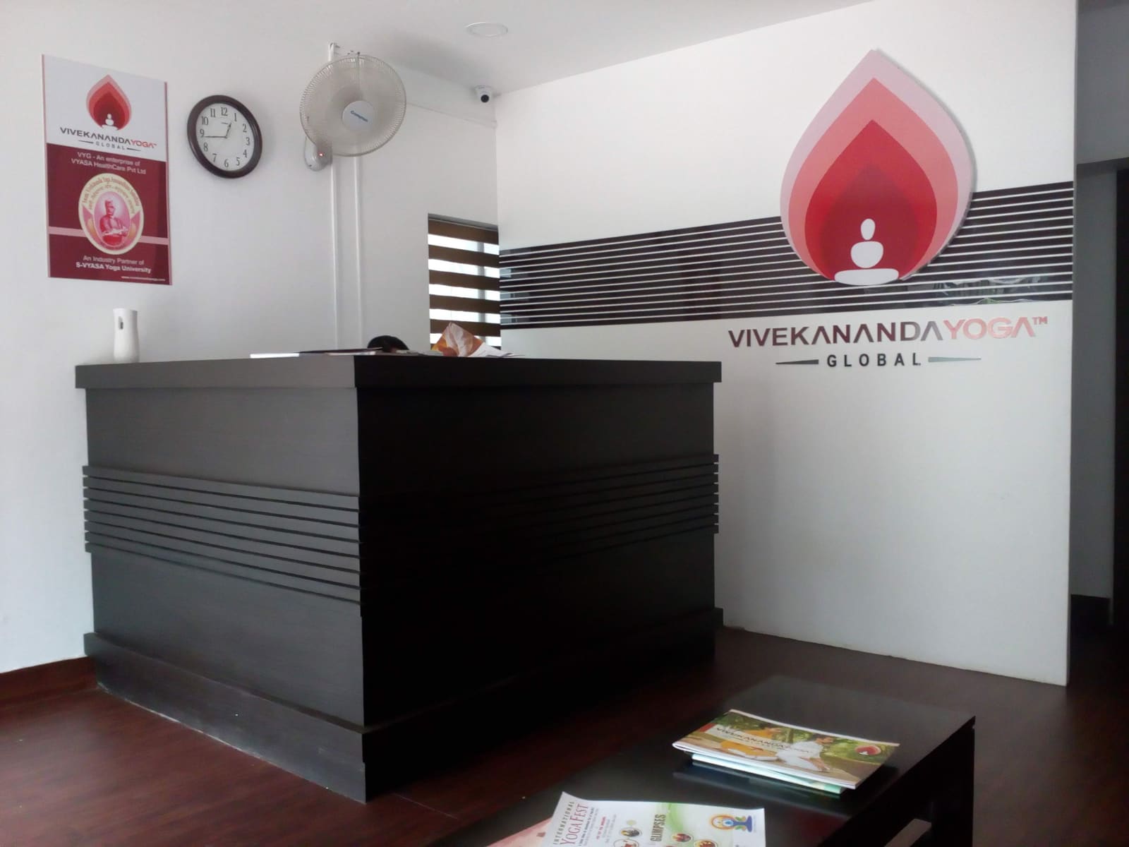 The reception desk at VHG Thiruvananthapuram, below the Vivekananda Yoga Global wall mark